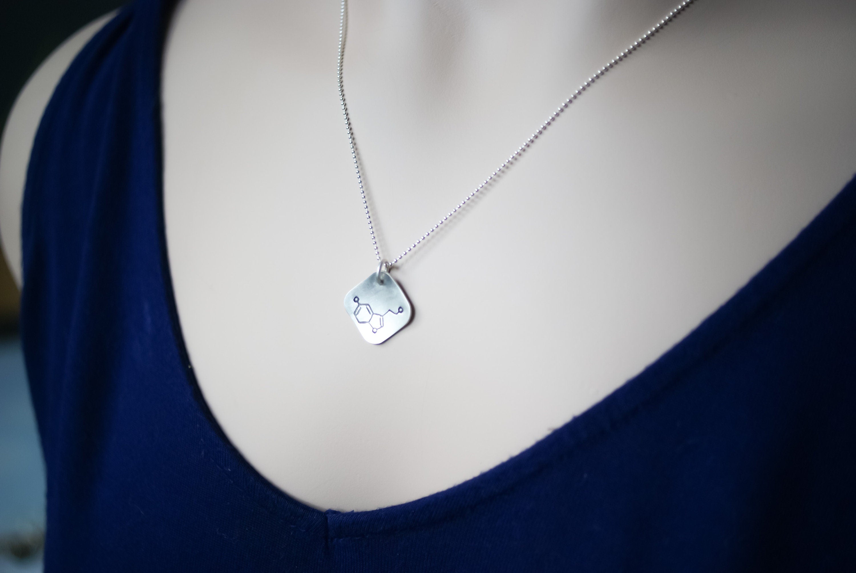 Sterling silver diamond shape necklace stamped with serotonin molecule on neck